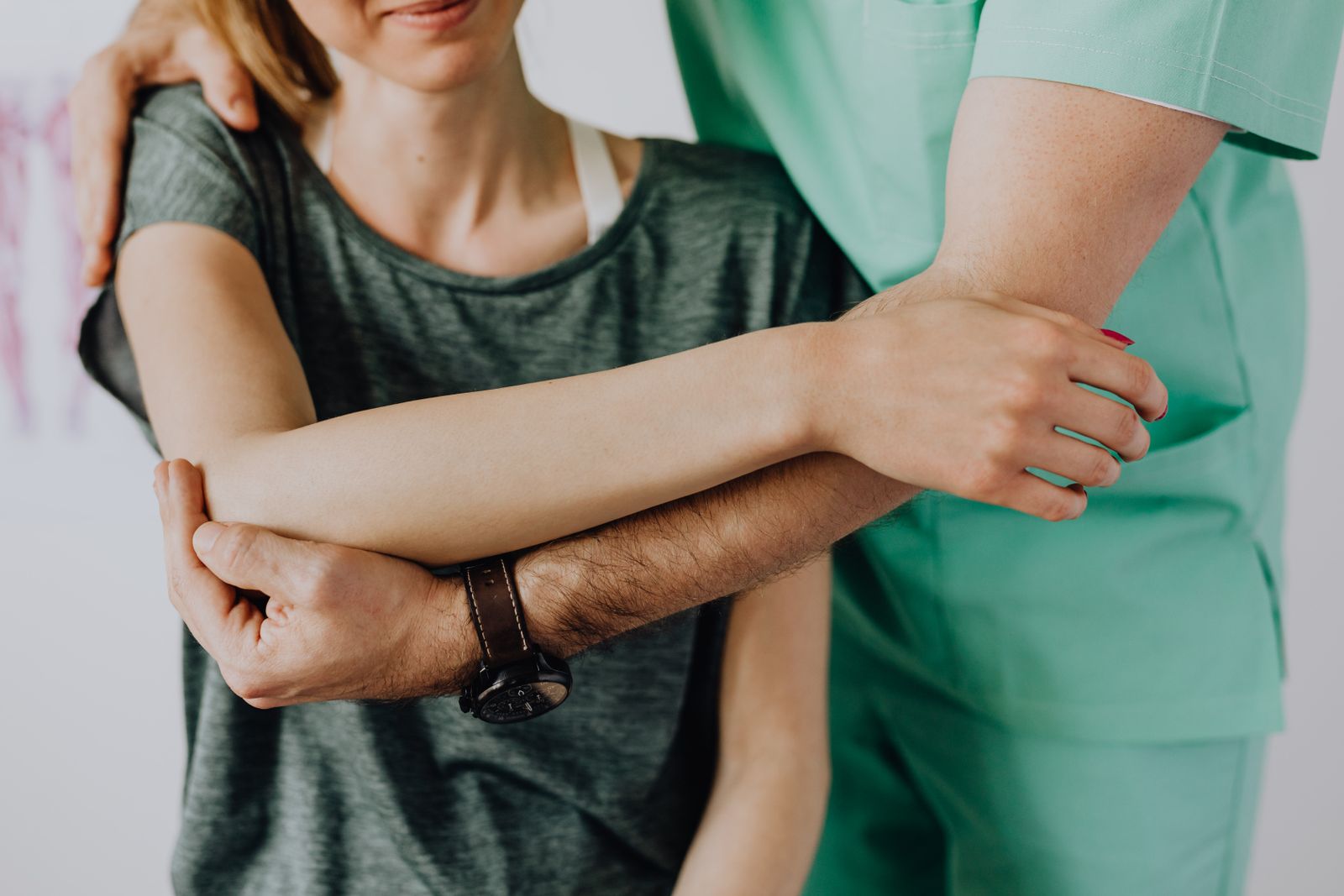 A chiropractor supports a woman's arm and shoulder while checking how it moves