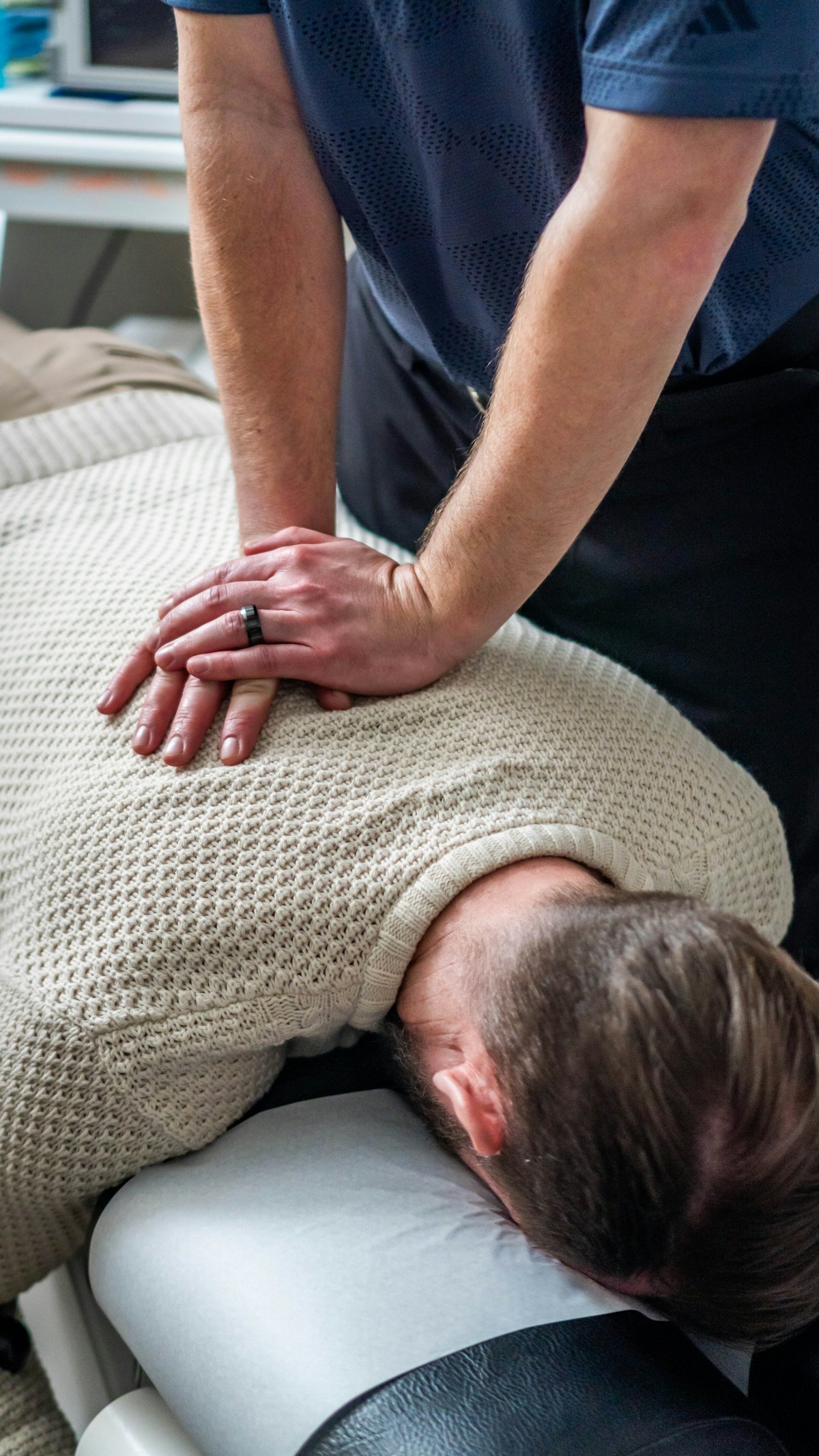 A chiropractor adjusting a man's upper back while he lies face down